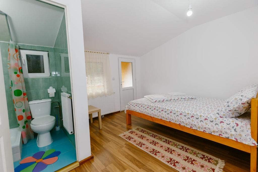 a small bedroom with a bed and a toilet at Casa Vio in Nehoiu