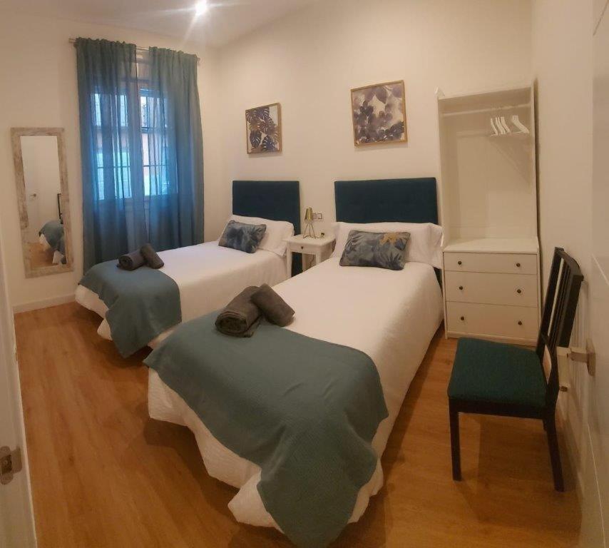 Un dormitorio con 2 camas y una silla. en Apartamento Roco en Madrid