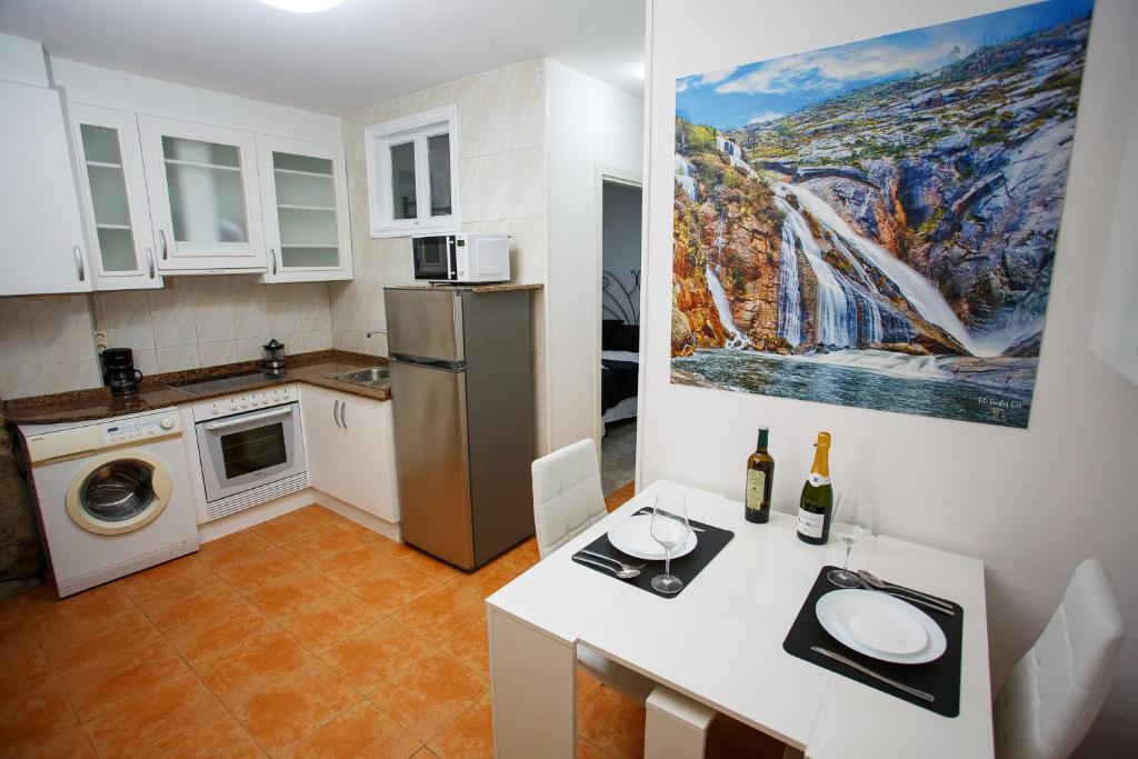 uma pequena cozinha com uma mesa e um frigorífico em A Casiña de Juan em Corcubión