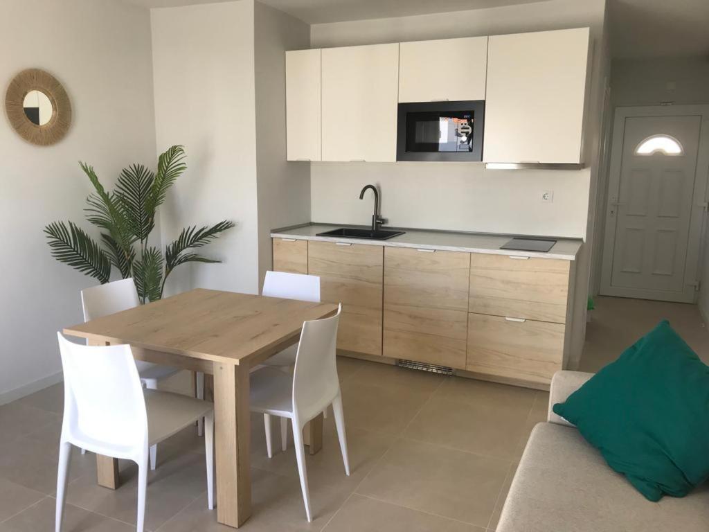 a kitchen with a wooden table and white cabinets at Casa Palmera in Costa de Antigua