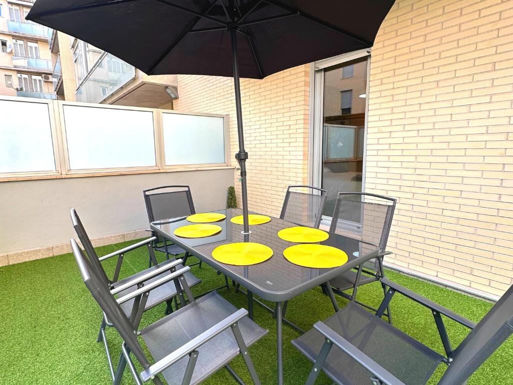 une table avec des chaises jaunes et un parasol dans l'établissement Dos Torres Las Comarcas - Amplia Terraza y Estacionamiento Gratuito, à Saragosse
