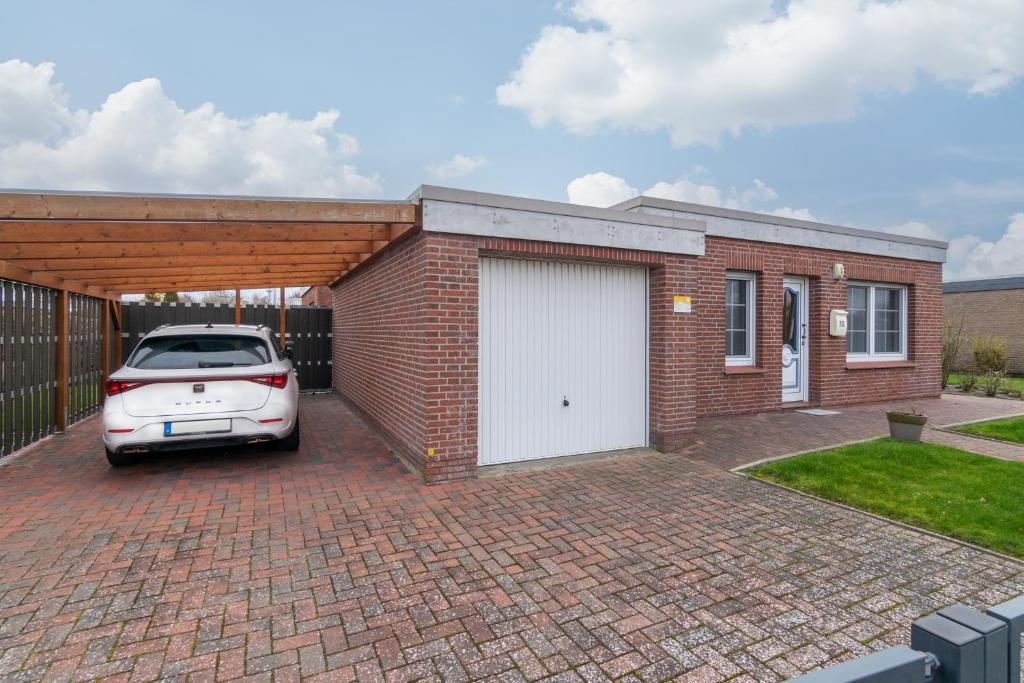 eine Backsteingarage mit einem Auto, das darin geparkt ist in der Unterkunft Ferienhaus Seeschwalbe in Norddeich