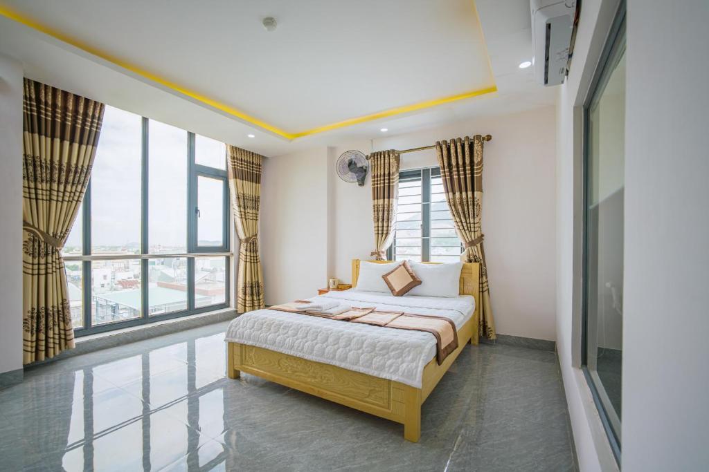 a bedroom with a bed and large windows at Phú Xuân Hotel in Quy Nhon