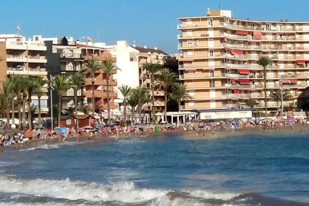 a crowd of people on a beach with buildings at Modern apartment in Torrevieja with terrace – 58 m² in Torrevieja