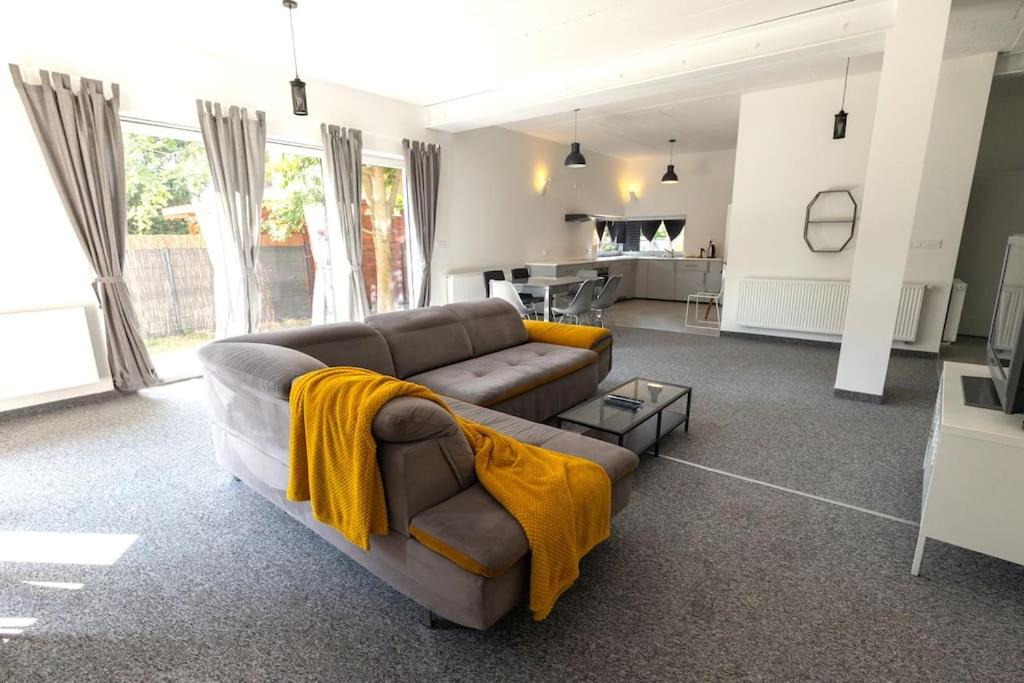 ein Wohnzimmer mit einem braunen Sofa und gelben Decken in der Unterkunft Modern 4 bedroom near Warsaw parking/wifi/200m2 in Marki
