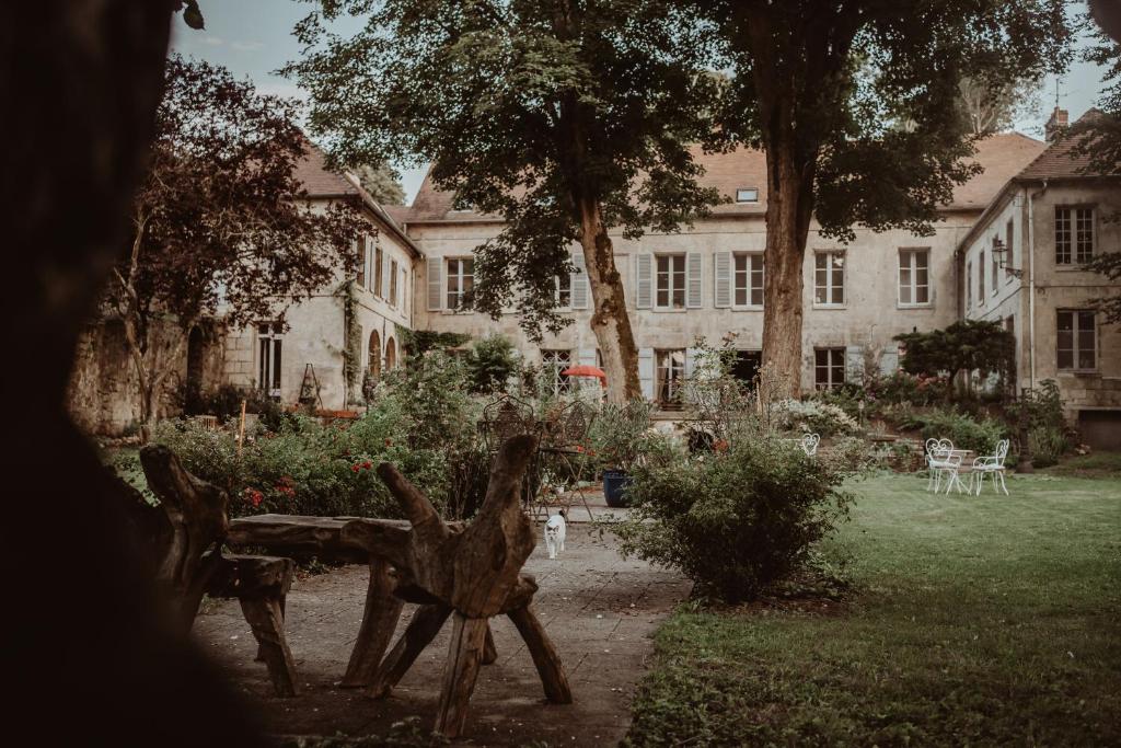 - une vue sur un bâtiment avec une cour dotée d'un banc dans l'établissement La Fontaine Racine - Chambres d'hôtes, à La Ferté-Milon