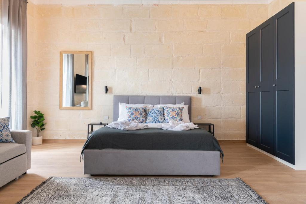 a bedroom with a bed and a couch and a wall at Valletta Collection - Felix Apartments in Valletta