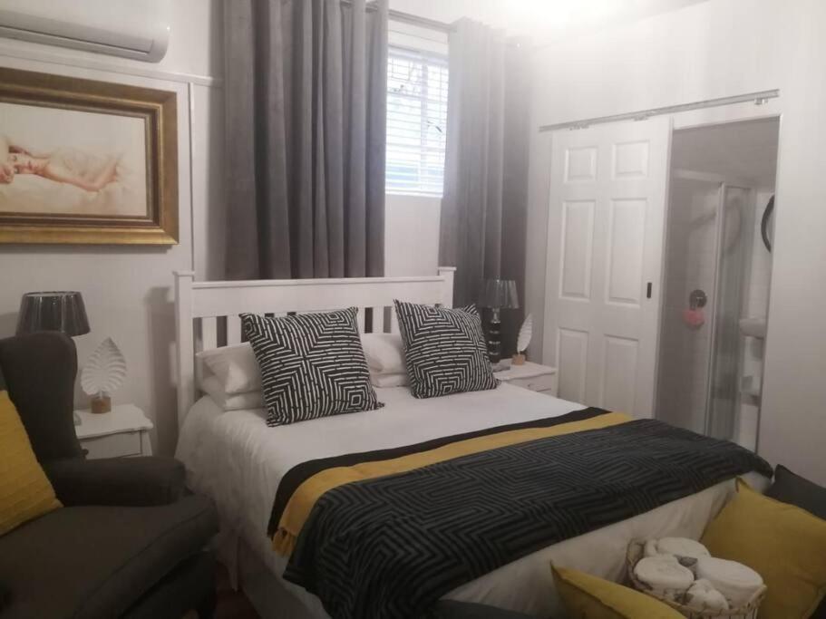 a bedroom with a bed with pillows and a chair at La Damon 2 in Paarl