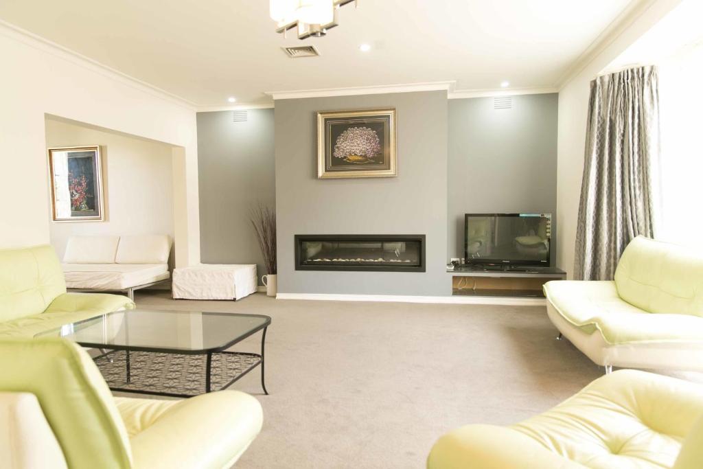 a living room with white furniture and a fireplace at Hawthorn Holiday House in Melbourne