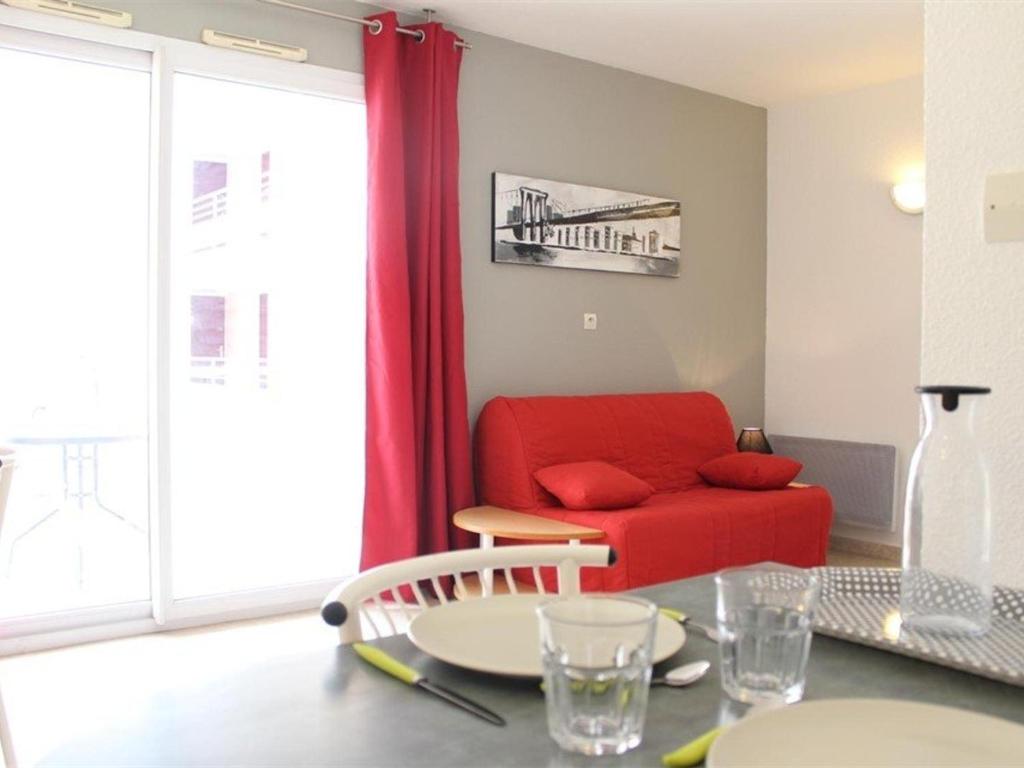 ラ・ロシェルにあるAppartement La Rochelle, 1 pièce, 2 personnes - FR-1-246-140のリビングルーム(赤いソファ、テーブル付)