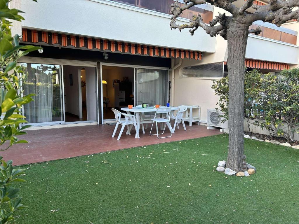 d'une terrasse avec une table, des chaises et un arbre. dans l'établissement Appartement T2 6 couchages avec jardin privé et terrasse au Grau-du-Roi, à deux pas de la mer - FR-1-250-223, au Grau-du-Roi
