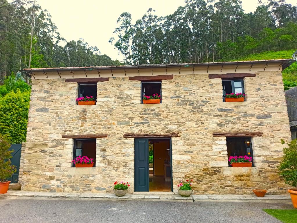 una casa de piedra con flores en las ventanas en Rego das Viñas, en Vivero