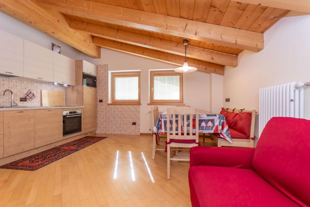 uma sala de estar com um sofá vermelho e uma cozinha em Casa Milena em Pozza di Fassa