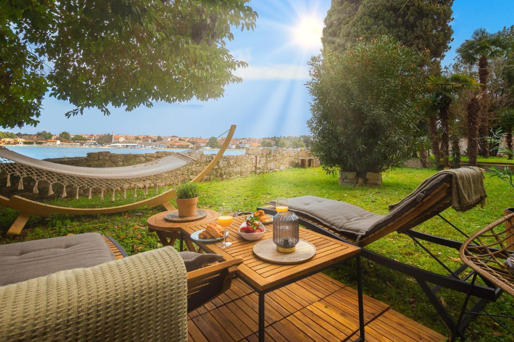un patio con mesa, sillas y hamaca en Exclusive Seafront Bacchus Apartment, en Poreč