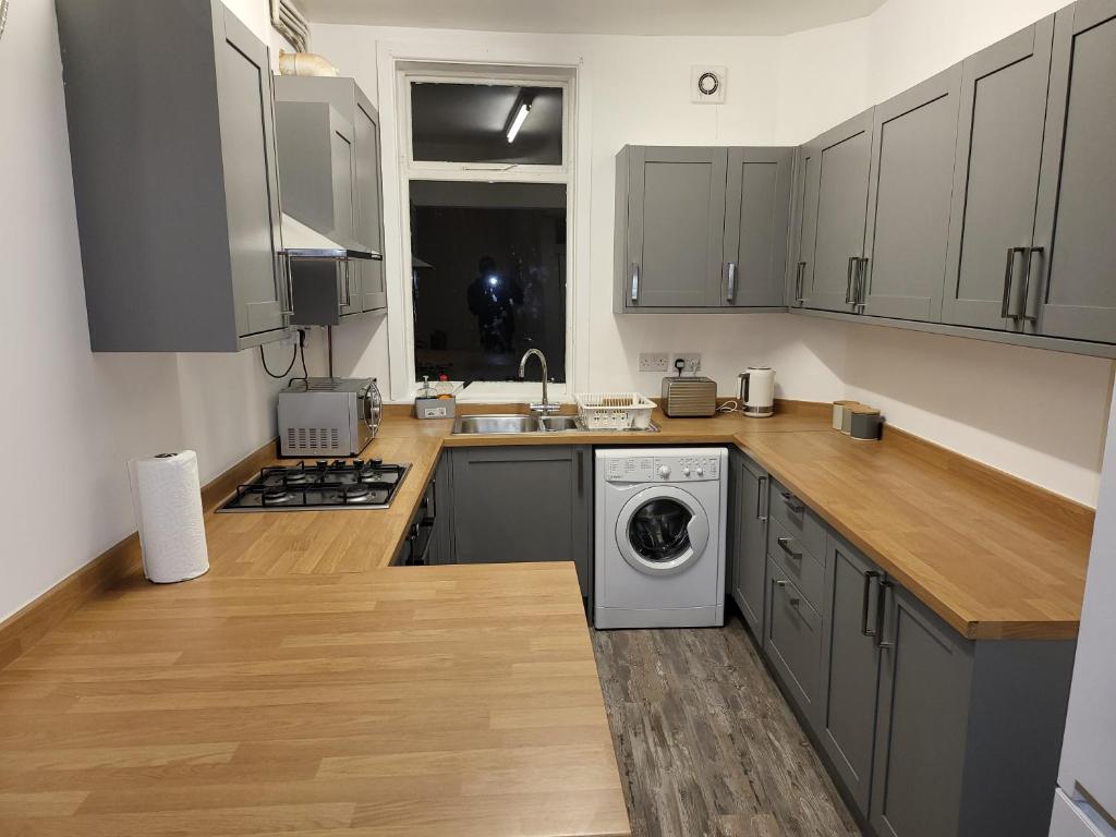 a kitchen with gray cabinets and a washer and dryer at Cheadle village in Cheadle