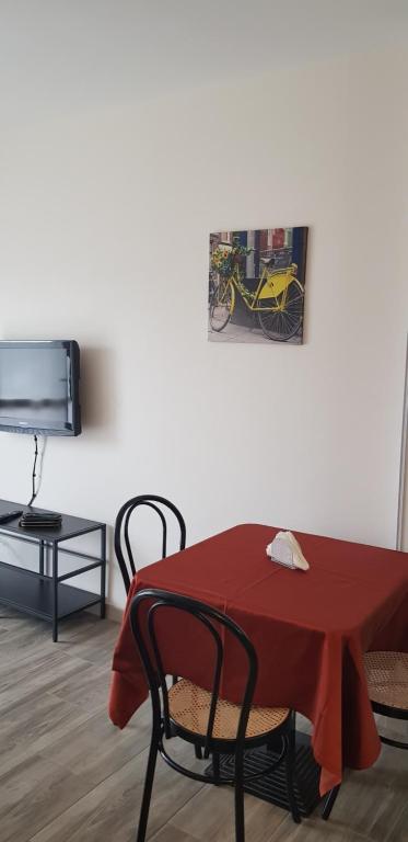 einen Tisch und Stühle mit einem roten Tisch und einem TV in der Unterkunft Appartamento San Miguel in Pasian di Prato