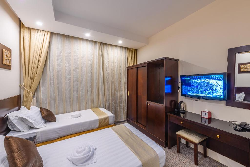 a hotel room with two beds and a television at Joury Al Mashaer Hotel in Makkah