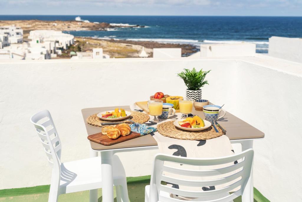 een tafel met eten en uitzicht op de oceaan bij Sweet Caleta in Caleta de Caballo