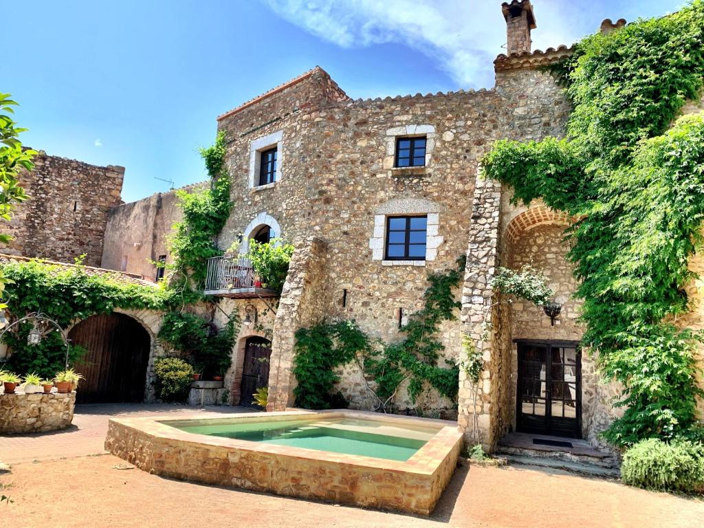 una vieja casa de piedra con una piscina frente a ella en ELS RACONS DEL FORT Castle in wine territory, en Capmany