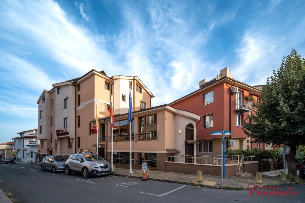 a building with cars parked in a parking lot at Hotel Chuchulev in Sozopol