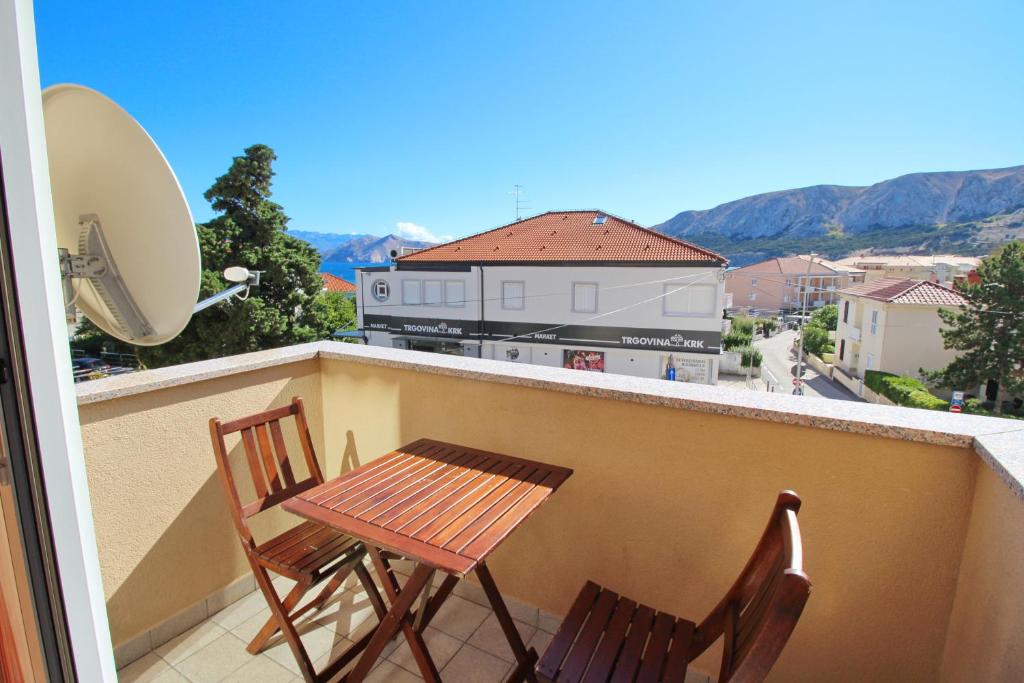 two chairs and a table on a balcony with a view at Apartment Smokvina P in Baška