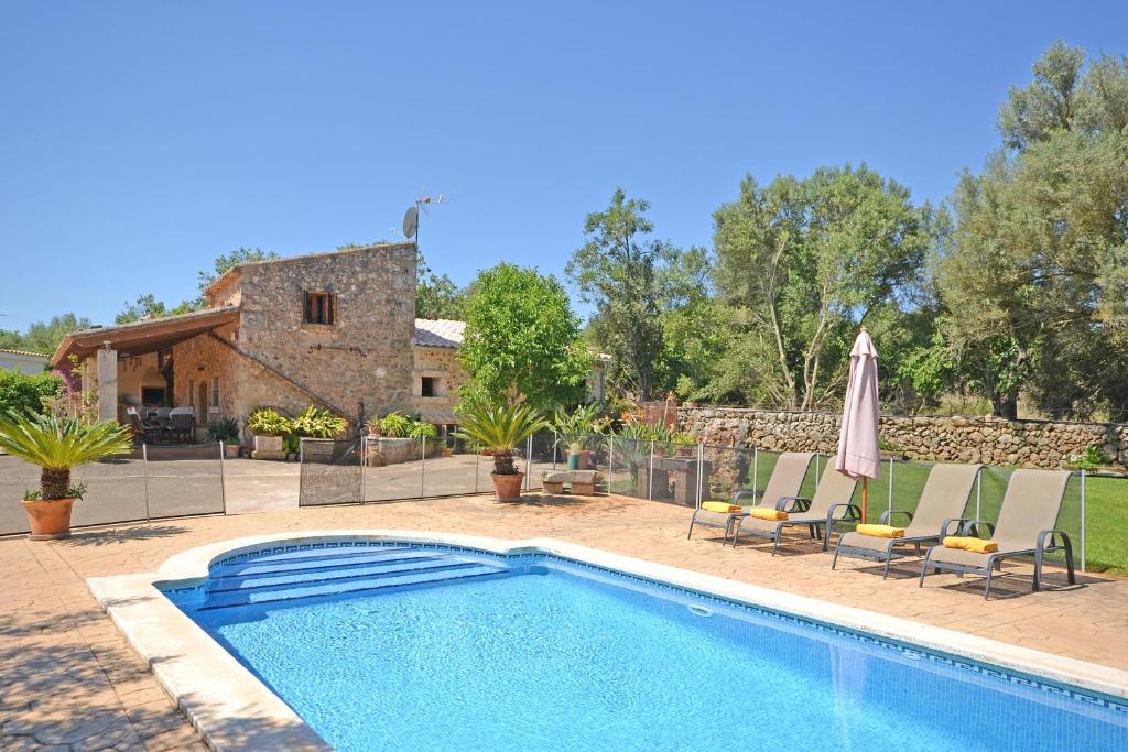 a swimming pool with chairs and a house at Villa Alba in Llubí