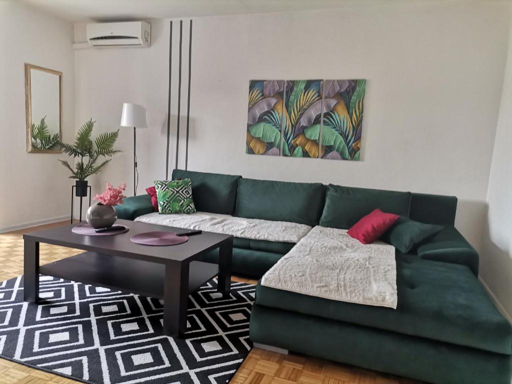 ein Wohnzimmer mit einem grünen Sofa und einem Tisch in der Unterkunft Apartment Melli in Sarajevo