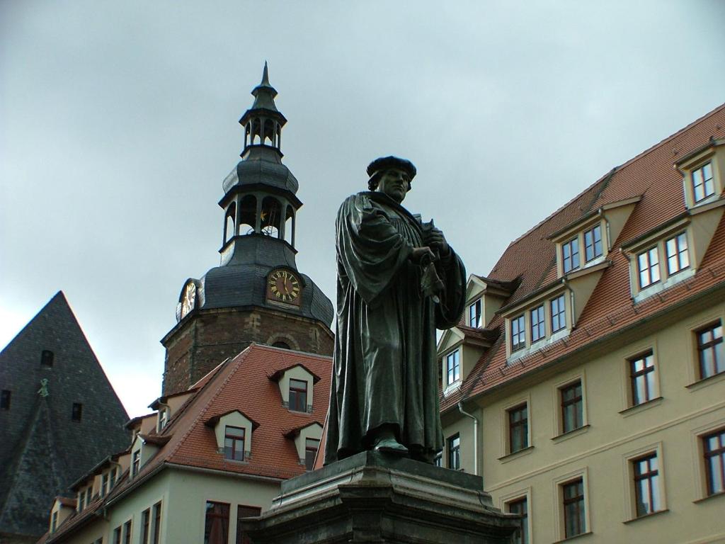a statue of a man standing in front of a building at Hotel garni Pension Zur Lutherstadt in Lutherstadt Eisleben