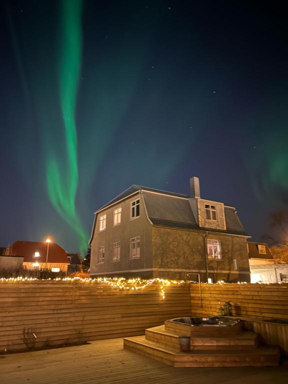 a house with the aurora in the sky behind it at Lovely Studio Apartment with Hot Tub in Reykjavík