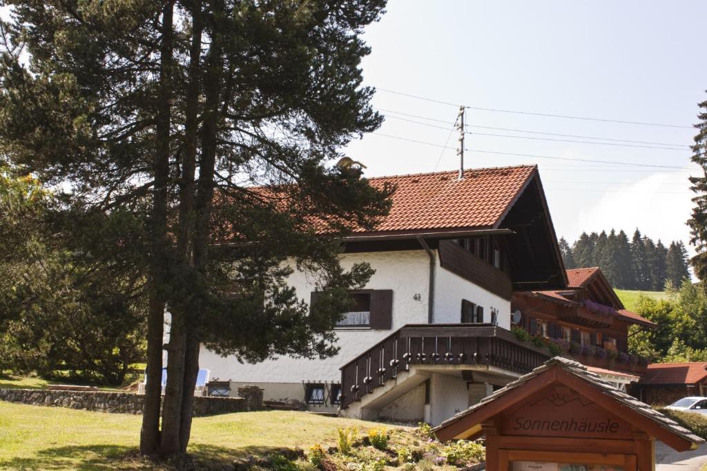 une grande maison blanche avec un toit rouge dans l'établissement Sonnenhäusle Klaus und Sabine Schmid, à Immenstadt
