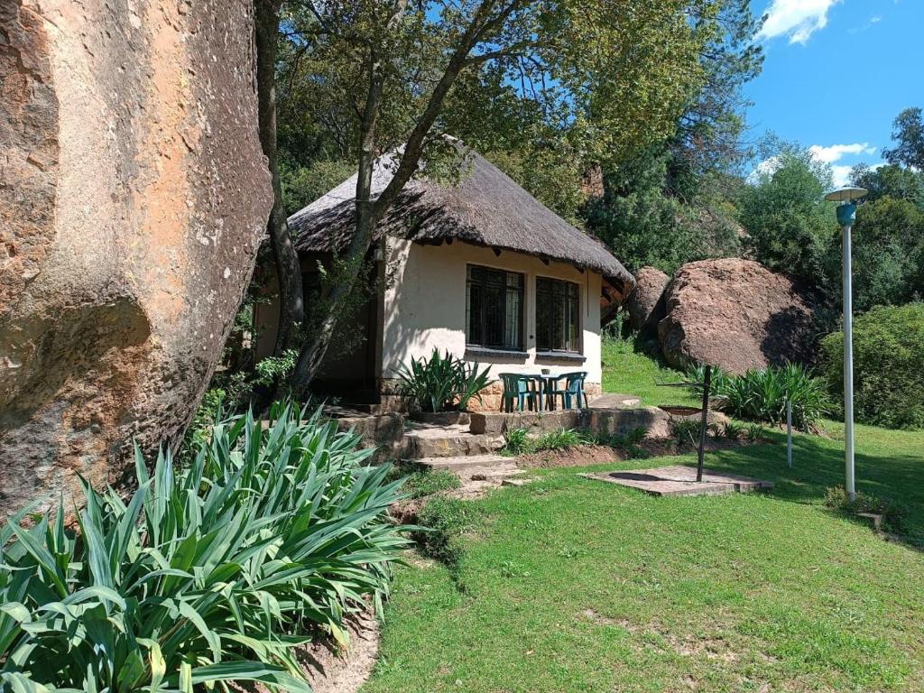 a small house with a thatched roof in a yard at Little Rock Resort in Ladybrand