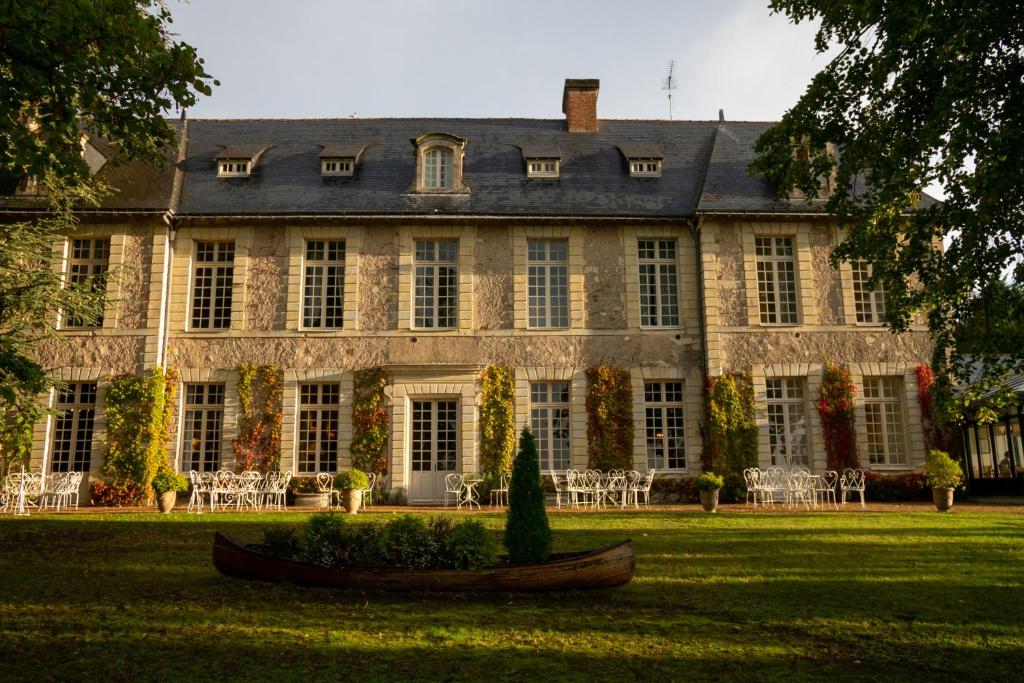 uma casa grande com um quintal com cadeiras e uma árvore em Château De Noirieux em Briollay