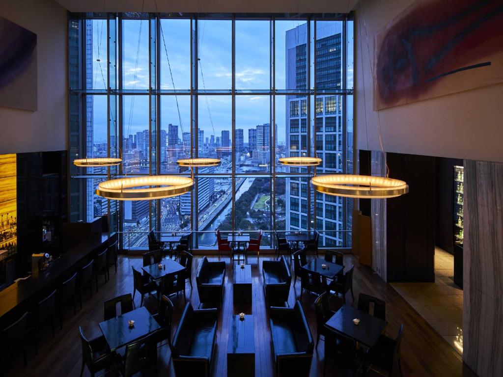 a restaurant with tables and chairs and a large window at The Royal Park Hotel Iconic Tokyo Shiodome in Tokyo