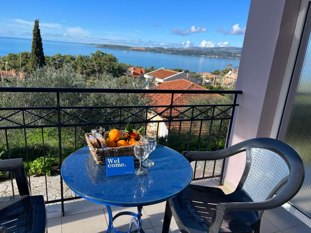 a table with a basket of fruit and wine glasses on a balcony at Alexandra’s Studios Sunset View in Argostoli