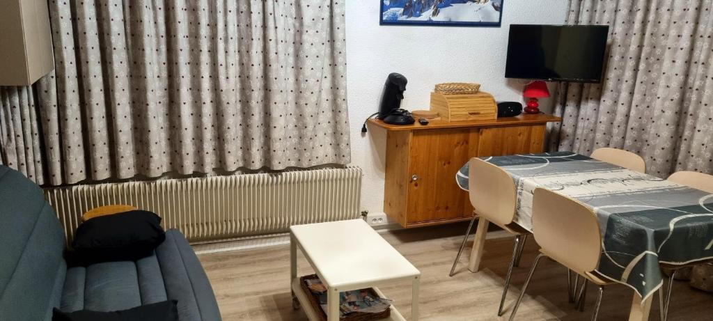 a room with a table and chairs and a television at Appartement d&#39;une chambre avec vue sur la ville balcon et wifi a Chamrousse in Chamrousse