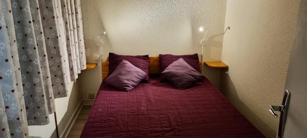 a small bed in a small room with purple pillows at Appartement d&#39;une chambre avec vue sur la ville balcon et wifi a Chamrousse in Chamrousse