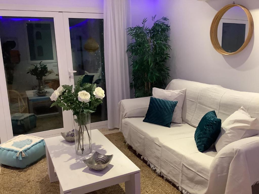 a living room with a white couch and a table with flowers at Apartamento Playa Denbossa in Playa d'en Bossa