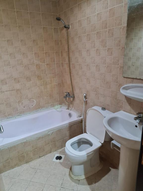 ein Badezimmer mit einem WC, einem Waschbecken und einer Badewanne in der Unterkunft Almond Tower, Garden City in Ajman 