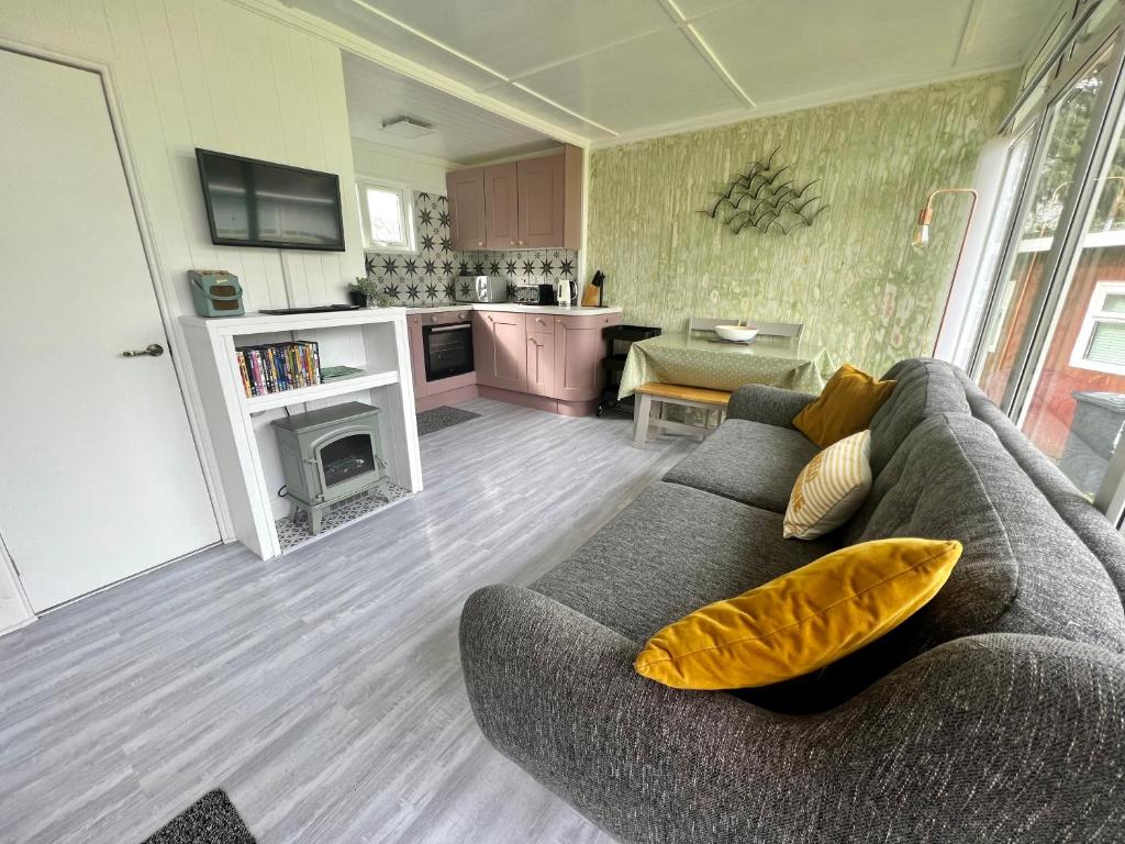 a living room with a gray couch and a kitchen at Shrimpy- A cute family friendly chalet in Cromer in Cromer