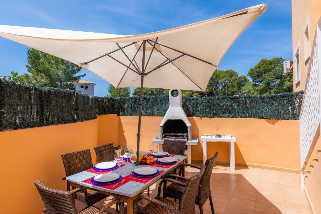 a table and chairs with an umbrella on a patio at Eulalia Beach in Can Picafort
