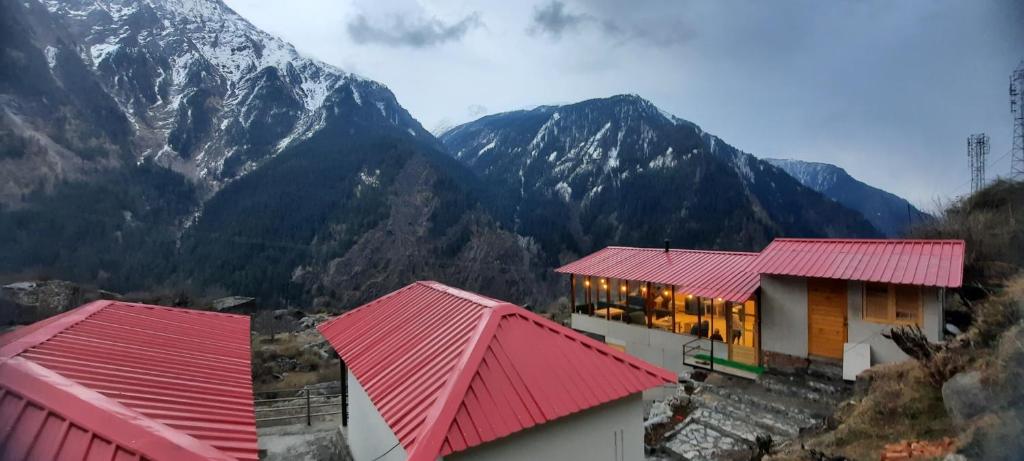 un edificio con techos rojos con una montaña en el fondo en Awana Cottages, en Harsil