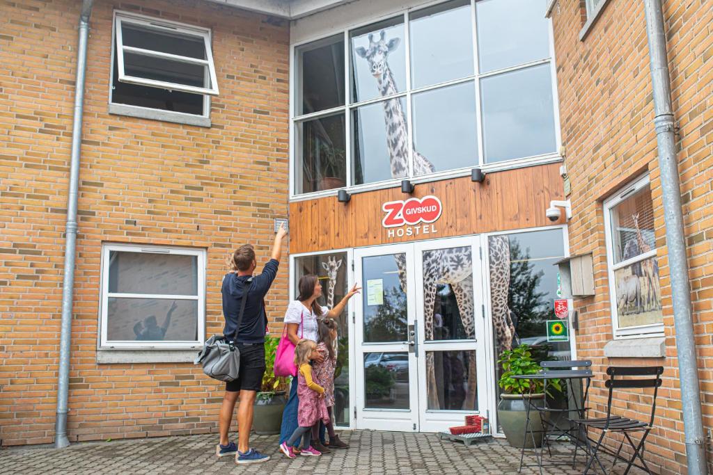 Duas mulheres à porta de um edifício de tijolos. em Givskud Zoo Hostel em Givskud