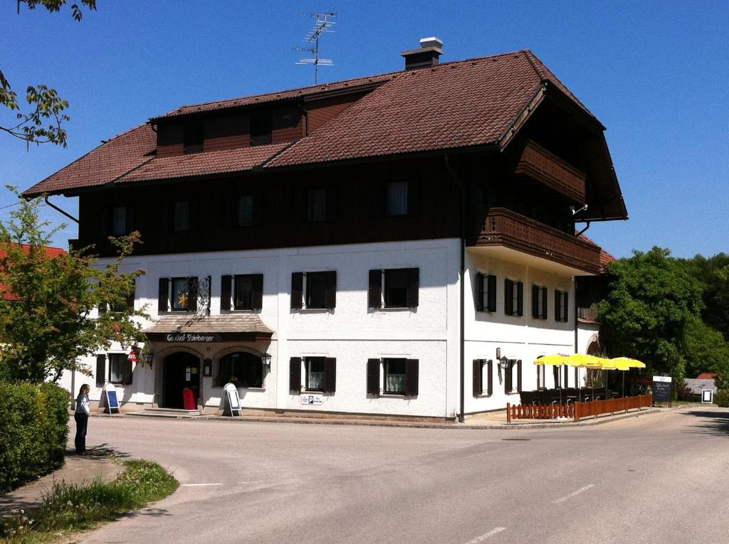 ein großes weißes Gebäude mit braunem Dach in der Unterkunft Gasthof Pension Steinberger in Sankt Georgen im Attergau