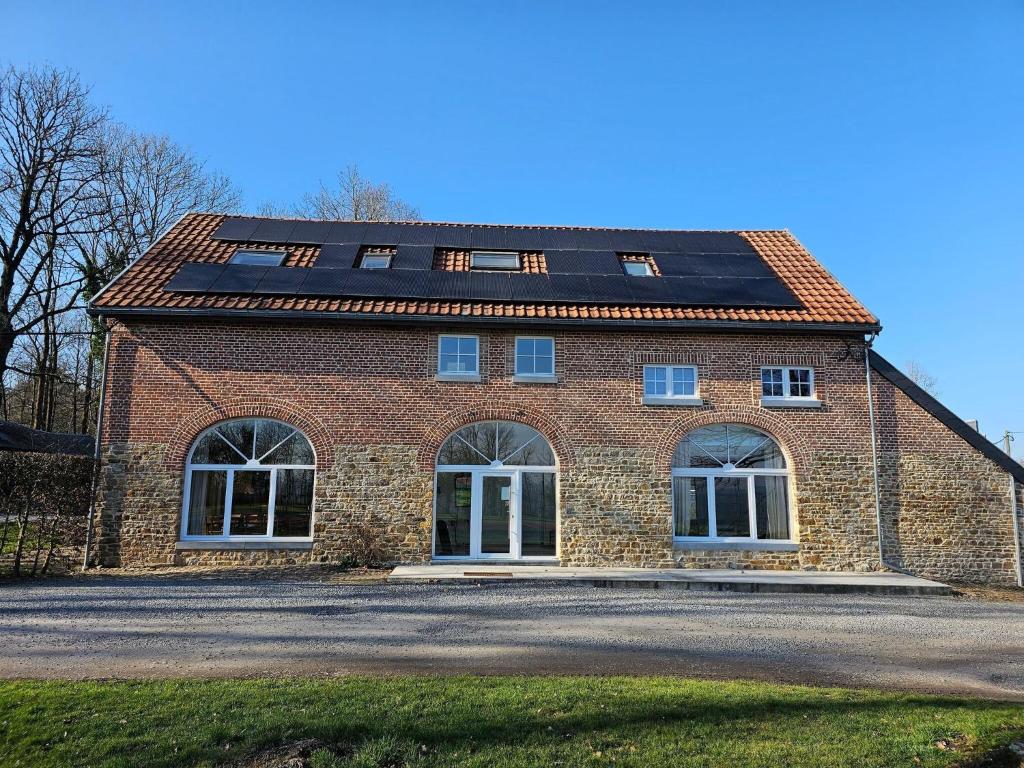 uma casa de tijolos com painéis solares no telhado em Spacious holiday home in Wallonie with terrace 