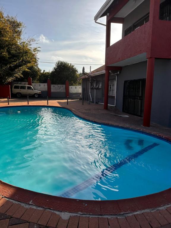 a large blue swimming pool in front of a house at L-PACK PRIMROSe in Germiston