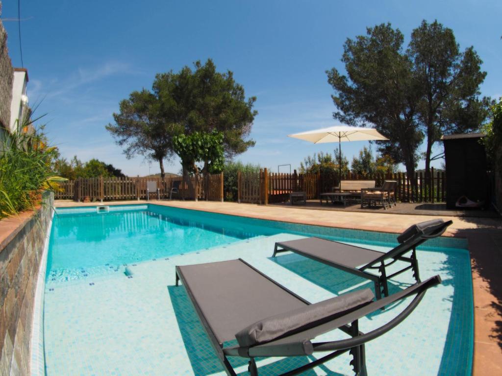 - une piscine avec 2 chaises longues et un parasol dans l'établissement Villa Can Xum by Hello Homes Sitges, à Canyelles