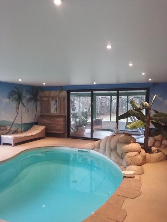 uma grande piscina numa casa com um quarto com janelas em LA LAUZERAIE em La Bourboule