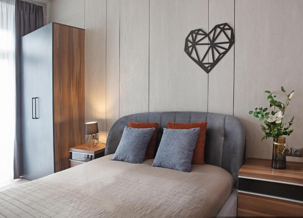 a bedroom with a bed with a heart hanging on the wall at Apartment & Parking "Opera at the corner" in Odesa