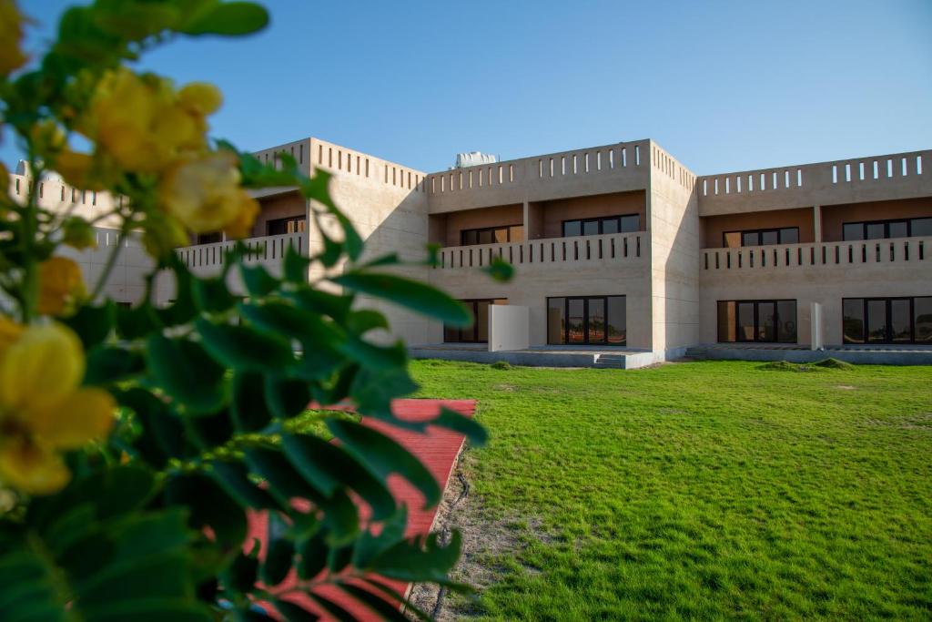 ein Gebäude mit grünem Rasen davor in der Unterkunft Continent Hotel Al Uqayr فندق كونتننت العقير 