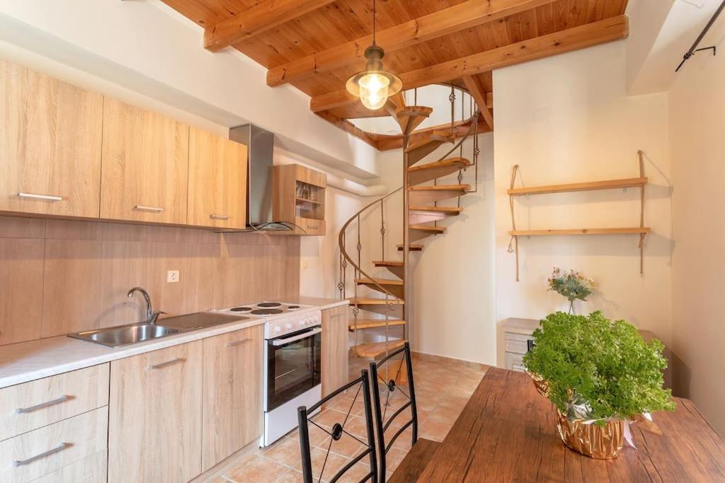 a kitchen with wooden cabinets and a spiral staircase at Elia Studio in Sokrákion